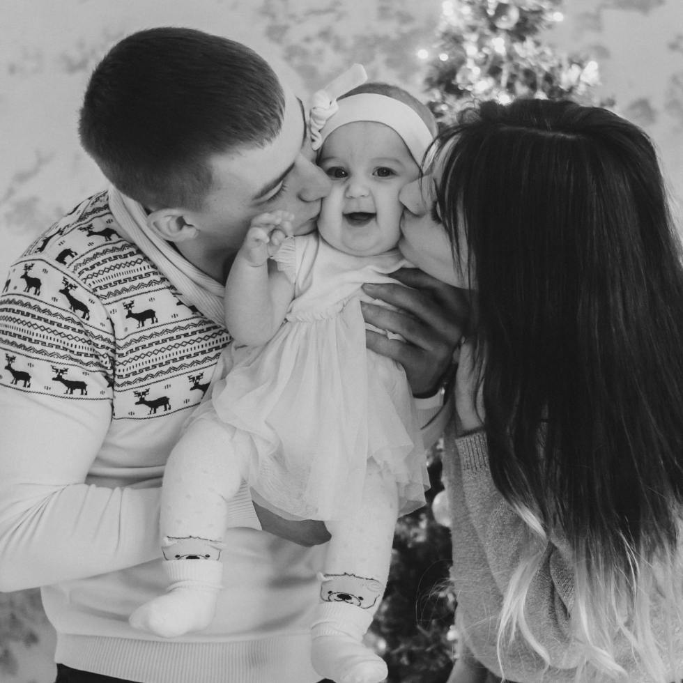 family kisses baby on the cheeks
