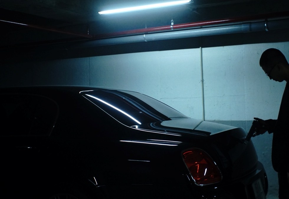 culture of guns man holding handgun standing at the back of a car