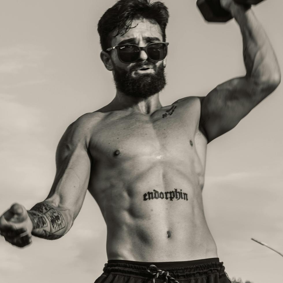 typical allusion to the manosphere, the picture shows a very sit male with a beard and sunglasses on lifting weights without his shirt on.