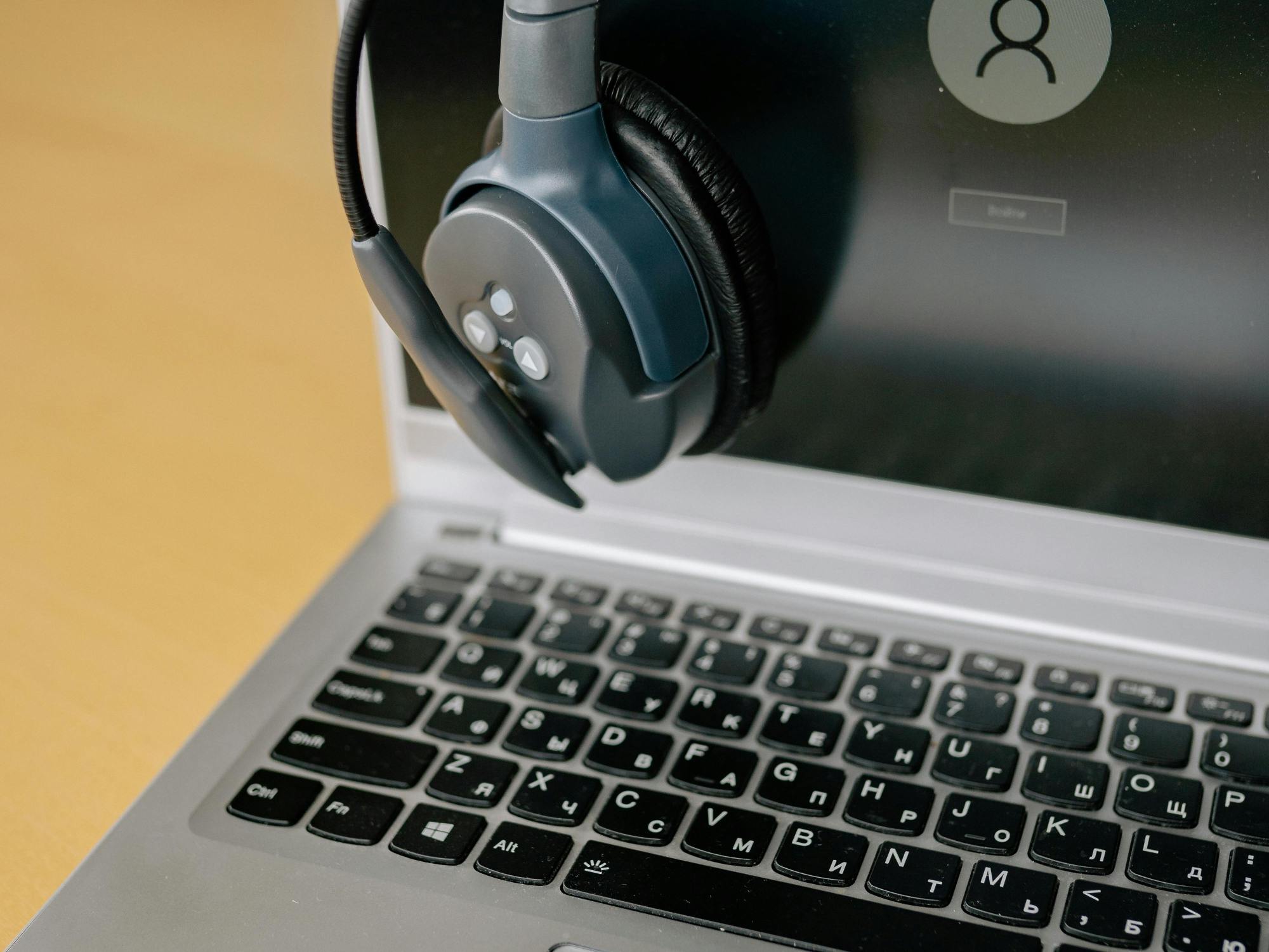 laptop ready for use, with a headset over them and a Windows login screen.