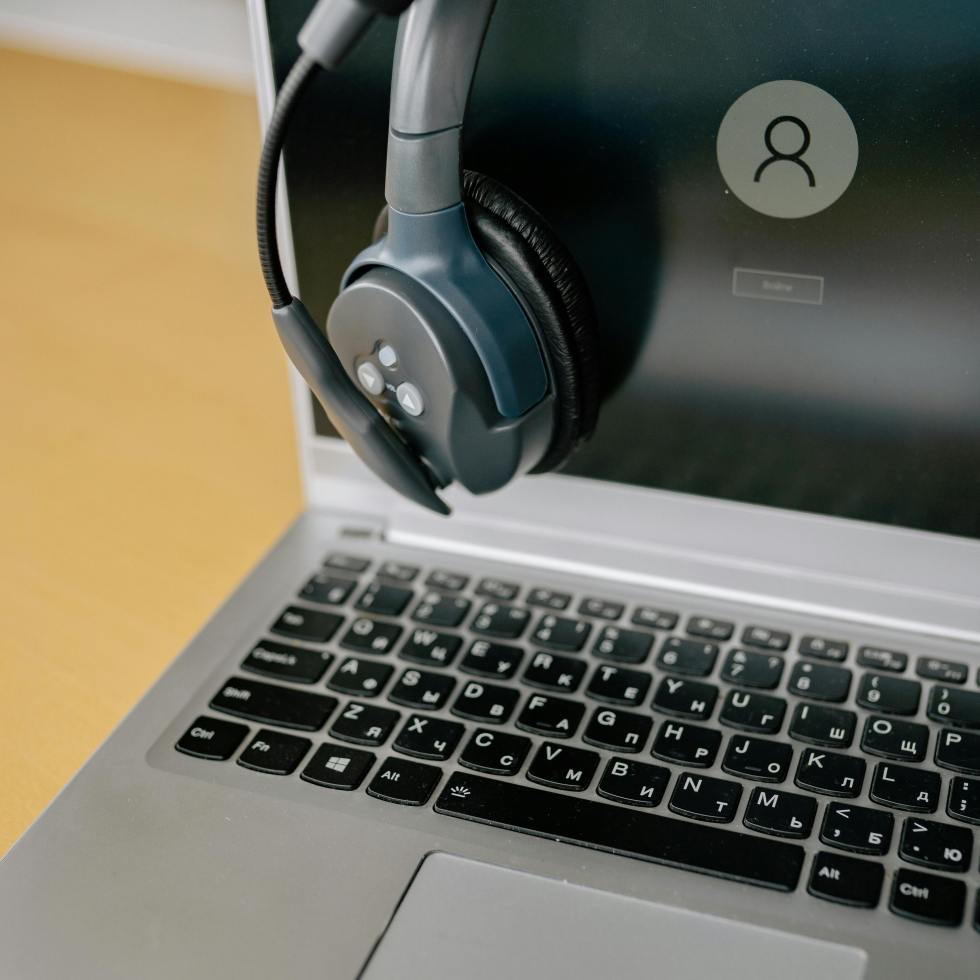 laptop ready for use, with a headset over them and a Windows login screen.