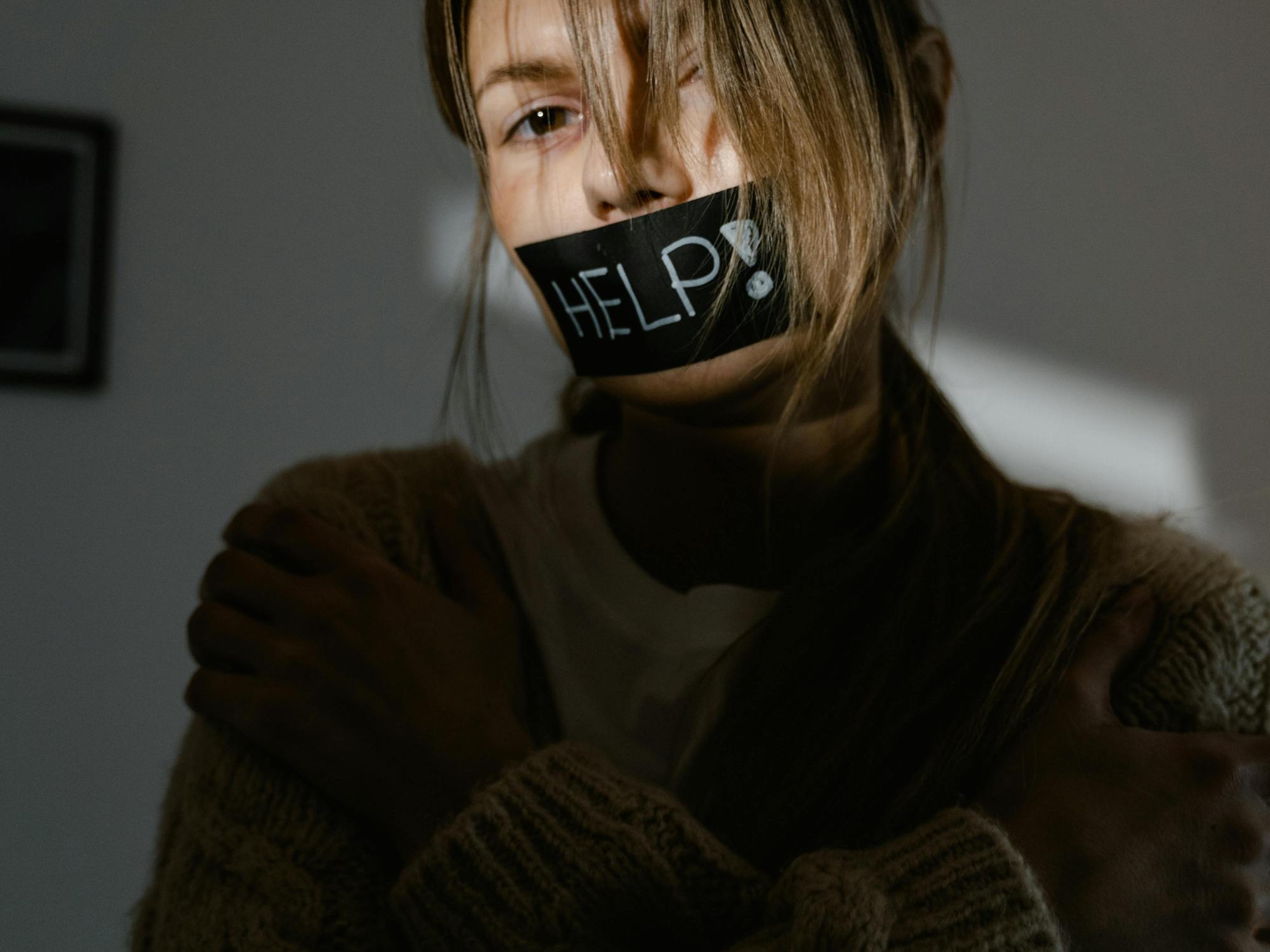 woman silently asks for help with a tape over her mouth